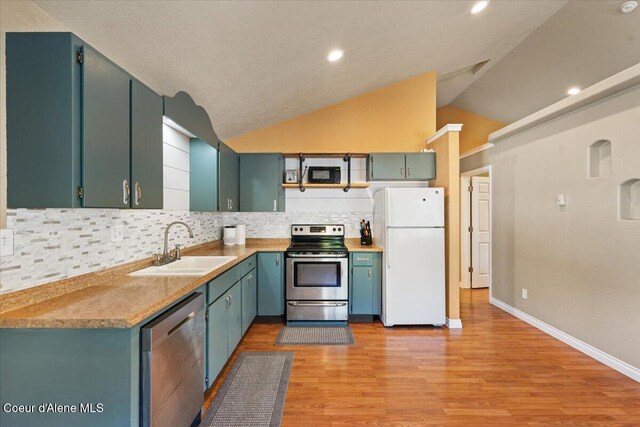 115 Fifth St, Osburn, ID 83849 - kitchen featuring appliances with stainless steel finishes, a sink, vaulted ceiling, decorative backsplash, and light wood finished floors