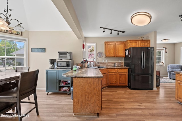 67 Spur Dr, Sandpoint, ID 83864 - kitchen with freestanding refrigerator, stainless steel microwave, a peninsula, light wood-type flooring, and healthy amount of natural light