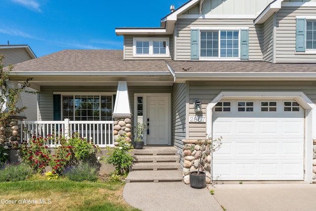 2867 W Tours Dr, Coeur Dalene, ID 83815 - view of front of property with an attached garage, a shingled roof, covered porch, and board and batten siding
