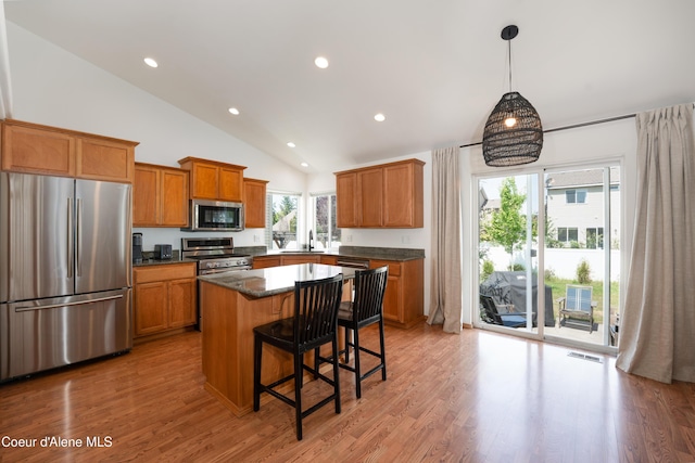 2867 W Tours Dr, Coeur Dalene, ID 83815 - kitchen featuring stainless steel appliances, brown cabinetry, a kitchen breakfast bar, lofted ceiling, and a kitchen island