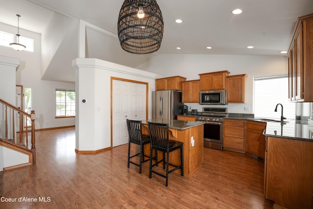 2867 W Tours Dr, Coeur Dalene, ID 83815 - kitchen with appliances with stainless steel finishes, a center island, dark countertops, high vaulted ceiling, and brown cabinetry