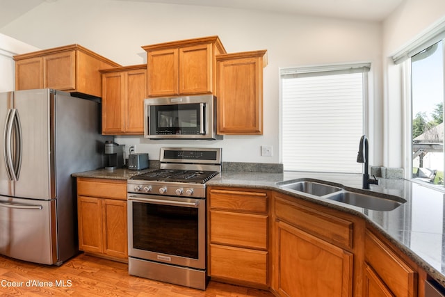 2867 W Tours Dr, Coeur Dalene, ID 83815 - kitchen featuring stainless steel appliances, light wood-style flooring, brown cabinetry, and vaulted ceiling