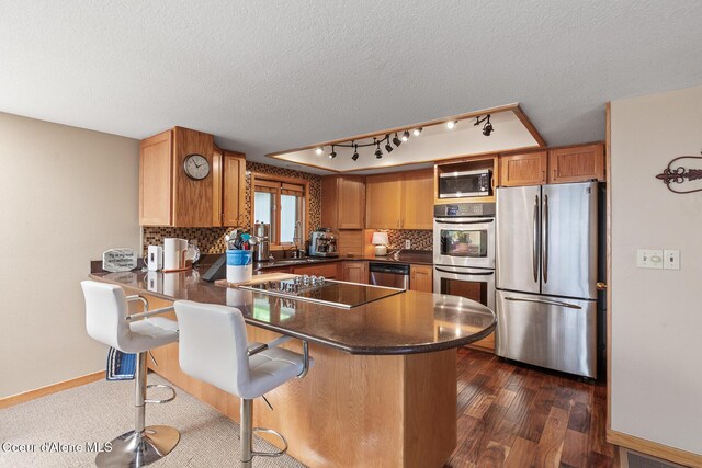 3574 E Tobler Rd # C16, Hayden, ID 83835 - kitchen with stainless steel appliances, a peninsula, a textured ceiling, tasteful backsplash, and dark countertops