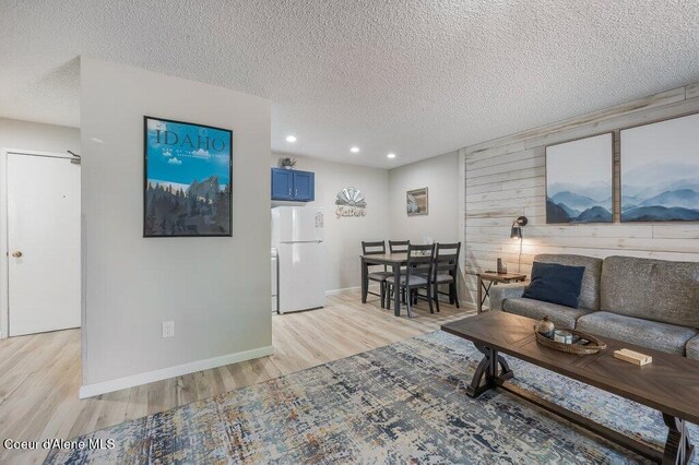 112 Holiday Loop Unit 838, Blanchard, ID 83804 - living room with light wood-style floors, a textured ceiling, baseboards, recessed lighting, and wooden walls