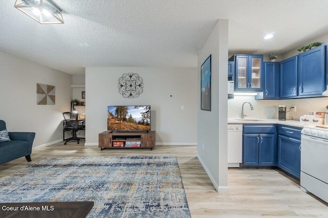 112 Holiday Loop Unit 838, Blanchard, ID 83804 - kitchen with blue cabinetry, a sink, white appliances, light countertops, and glass insert cabinets