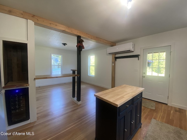 118 Faye St, Mullan, ID 83846 - kitchen with a wall mounted AC, butcher block countertops, wood finished floors, beamed ceiling, and dark cabinetry