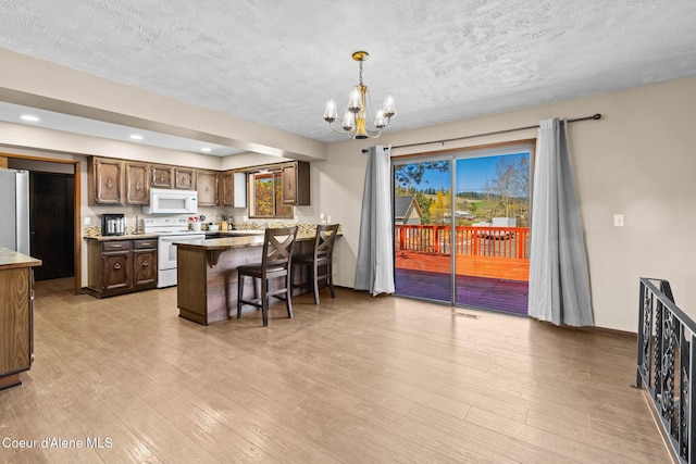 1364 C St, Plummer, ID 83851 - kitchen featuring white appliances, a chandelier, a peninsula, a textured ceiling, and light wood-type flooring