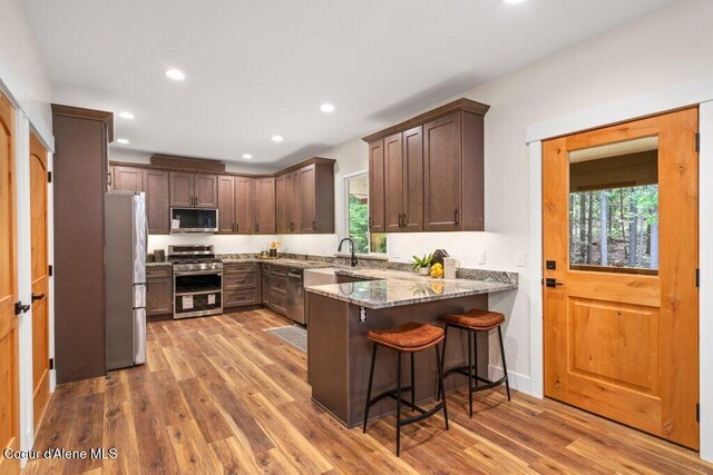 122 Cottonwood Dr, Sagle, ID 83860 - kitchen featuring stainless steel appliances, a peninsula, recessed lighting, wood finished floors, and light stone countertops