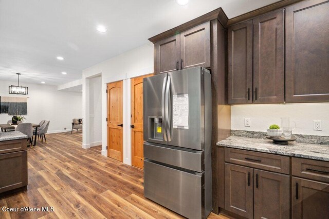 122 Cottonwood Dr, Sagle, ID 83860 - kitchen with stainless steel fridge with ice dispenser, recessed lighting, dark brown cabinets, wood finished floors, and light stone counters