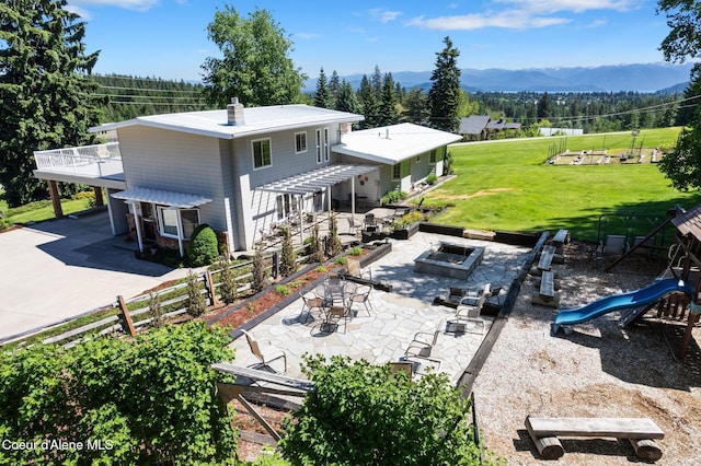 10851 W Pine St, Sandpoint, ID 83864 - rear view of house featuring an outdoor fire pit, a mountain view, a patio, driveway, and a playground