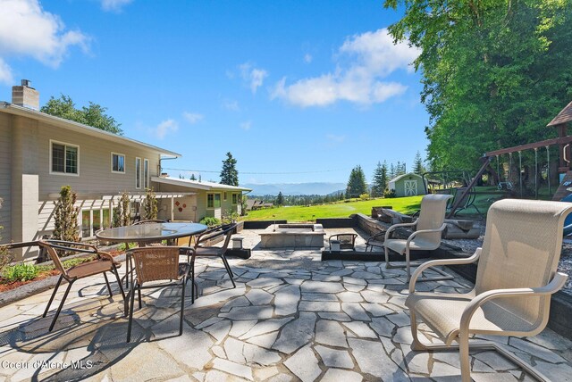10851 W Pine St, Sandpoint, ID 83864 - view of patio featuring a storage unit, a playground, and outdoor dining area