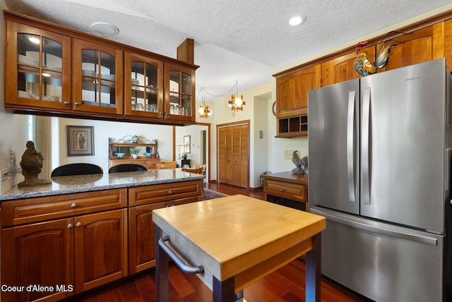 10851 W Pine St, Sandpoint, ID 83864 - kitchen featuring freestanding refrigerator, a textured ceiling, glass insert cabinets, brown cabinetry, and pendant lighting