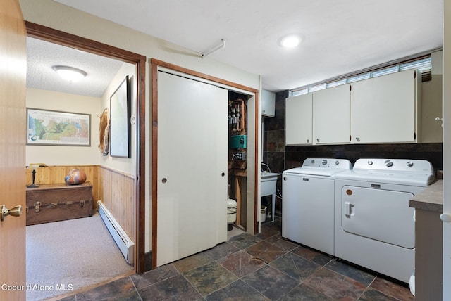 10851 W Pine St, Sandpoint, ID 83864 - washroom with cabinet space, a baseboard heating unit, washer and clothes dryer, wainscoting, and dark stone finish floors