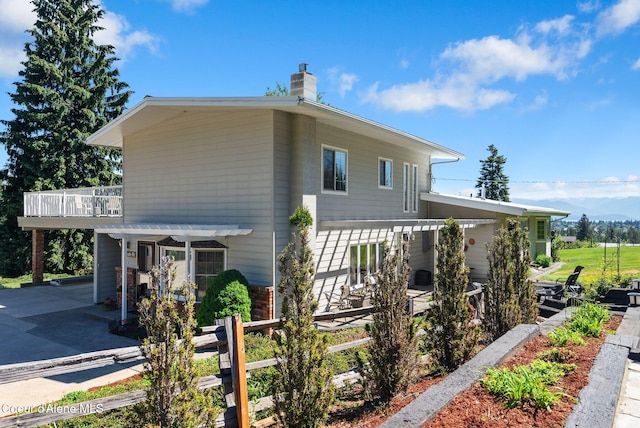 10851 W Pine St, Sandpoint, ID 83864 - view of side of property with a pergola, a chimney, a patio area, and a mountain view