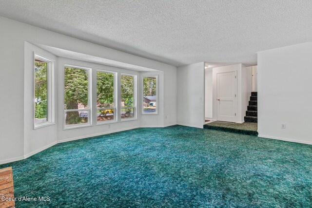 221 S Ridgewood Dr, Post Falls, ID 83854 - carpeted empty room with healthy amount of natural light, a textured ceiling, and stairs