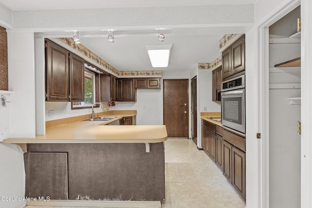 221 S Ridgewood Dr, Post Falls, ID 83854 - kitchen with oven, a peninsula, light countertops, dark brown cabinetry, and light floors