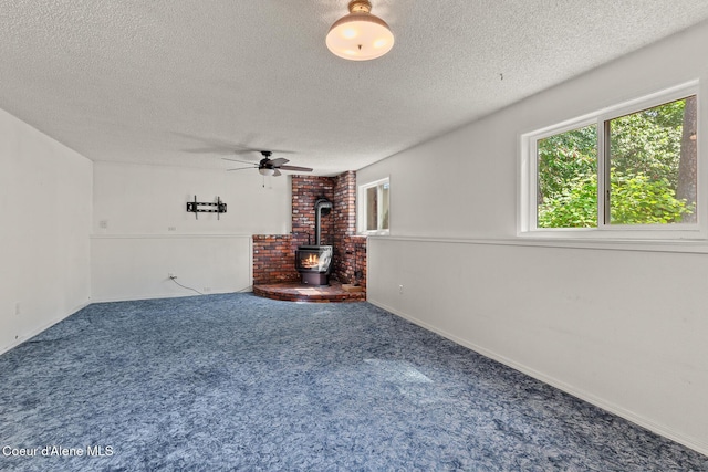 221 S Ridgewood Dr, Post Falls, ID 83854 - unfurnished living room featuring a wood stove, a textured ceiling, ceiling fan, and carpet flooring
