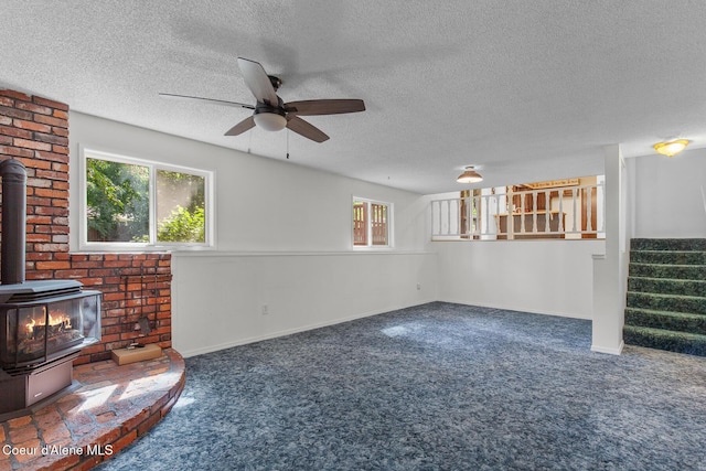 221 S Ridgewood Dr, Post Falls, ID 83854 - unfurnished living room featuring a wood stove, carpet, stairway, ceiling fan, and a textured ceiling