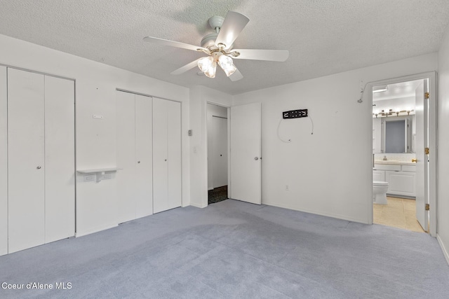 221 S Ridgewood Dr, Post Falls, ID 83854 - unfurnished bedroom with two closets, a textured ceiling, light carpet, ensuite bathroom, and a ceiling fan
