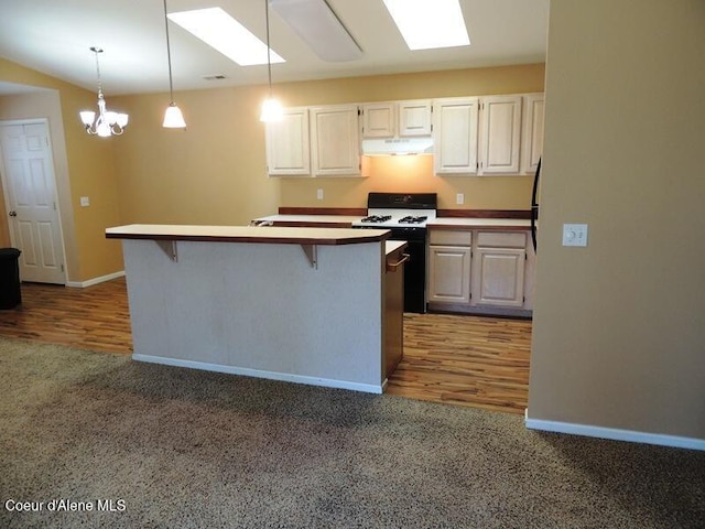 3696 N Steven Pl, Coeur Dalene, ID 83815 - kitchen featuring under cabinet range hood, a skylight, range with gas cooktop, carpet floors, and a breakfast bar