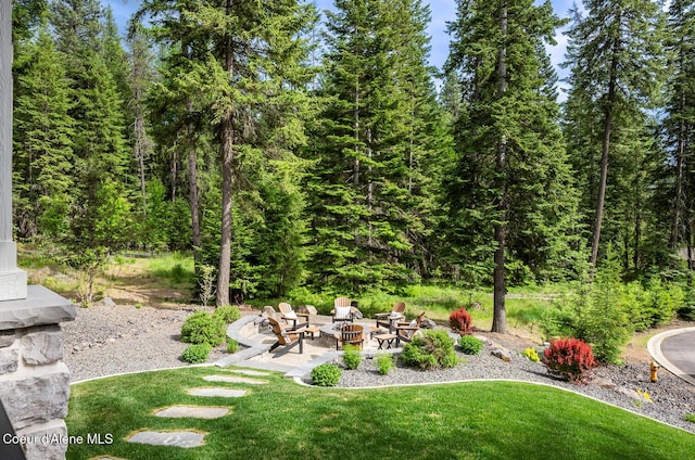 6767 S Renaissance Way, Coeur Dalene, ID 83814 - view of green lawn with an outdoor fire pit, a view of trees, and a patio