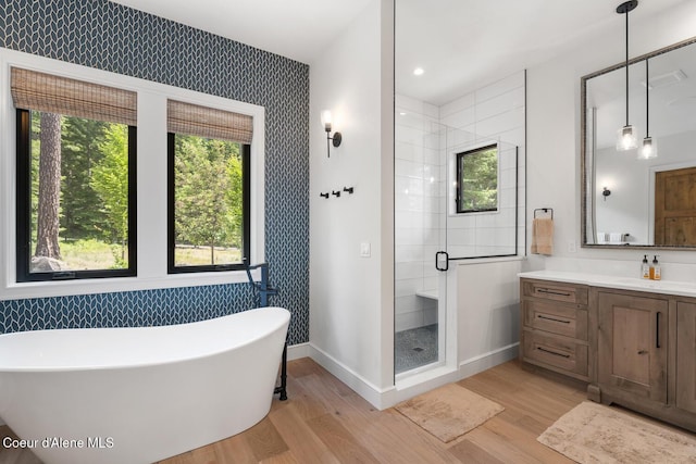 6767 S Renaissance Way, Coeur Dalene, ID 83814 - full bathroom with a freestanding tub, a stall shower, wood finished floors, vanity, and wallpapered walls