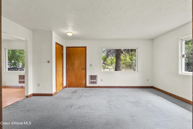 206 E 2nd Ave, Clark Fork, ID 83811 - unfurnished room featuring heating unit, carpet flooring, baseboards, and a textured ceiling