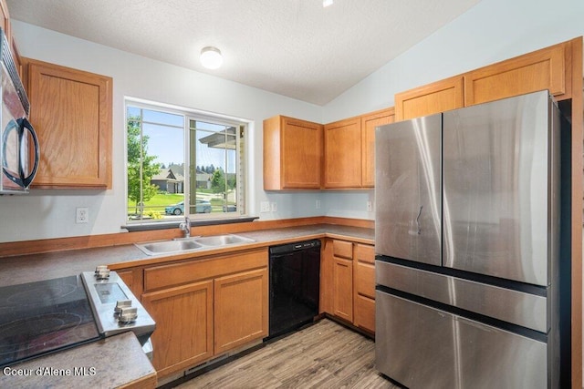 3551 N Carriage Ct, Post Falls, ID 83854 - kitchen with freestanding refrigerator, dishwasher, vaulted ceiling, range, and light wood-type flooring