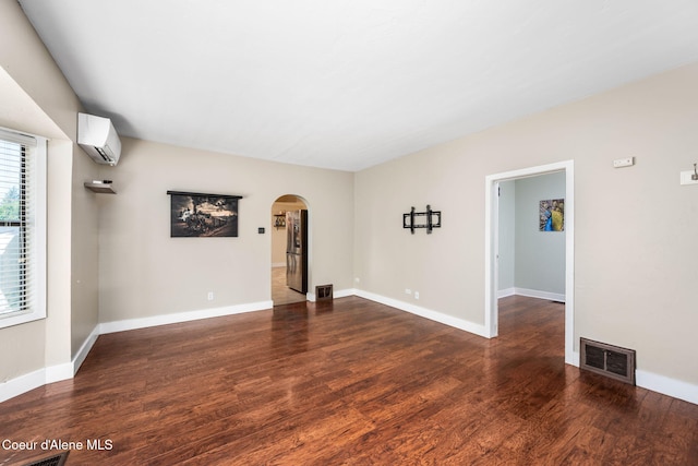 1215 N A St, Coeur Dalene, ID 83814 - unfurnished room featuring a wall unit AC, arched walkways, and wood finished floors