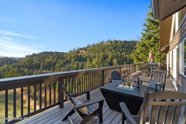 3889 E Avery Ln, Coeur Dalene, ID 83814 - wooden terrace featuring a view of trees, outdoor dining area, and a fire pit