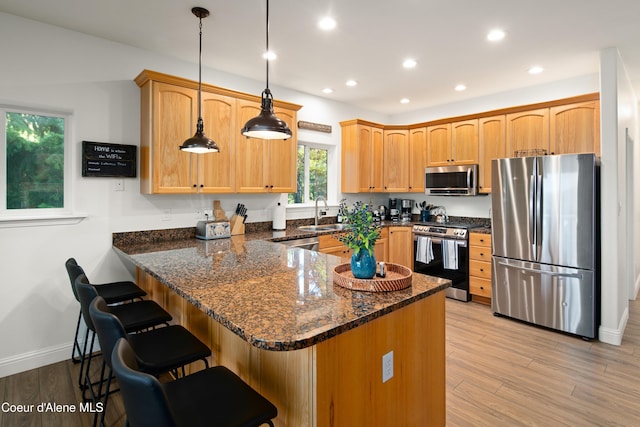 3889 E Avery Ln, Coeur Dalene, ID 83814 - kitchen featuring appliances with stainless steel finishes, a peninsula, dark stone counters, light wood-style flooring, and a breakfast bar