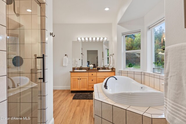 3889 E Avery Ln, Coeur Dalene, ID 83814 - bathroom with double vanity, a bath, a stall shower, wood finished floors, and recessed lighting