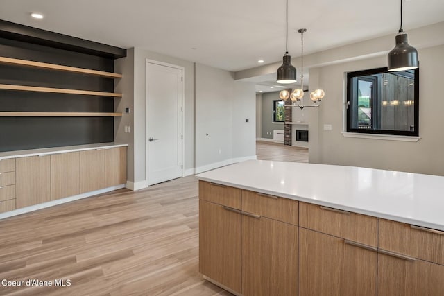 503 Cedar St # 203, Sandpoint, ID 83864 - kitchen featuring light wood-type flooring, light countertops, recessed lighting, hanging light fixtures, and a glass covered fireplace