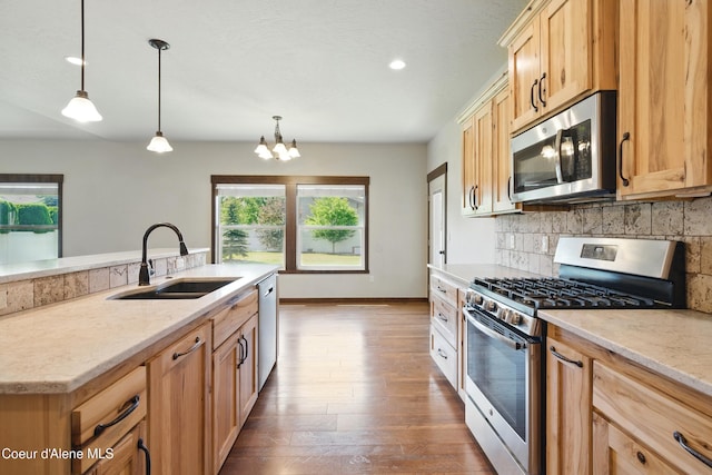 6984 W Blacktail Ave, Rathdrum, ID 83858 - kitchen with stainless steel appliances, tasteful backsplash, dark wood-style floors, light stone counters, and hanging light fixtures