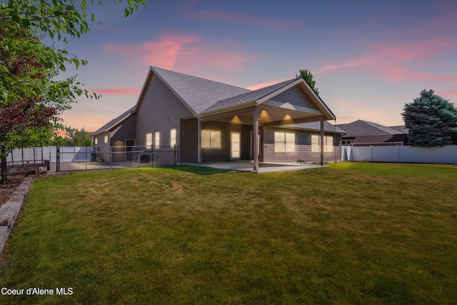 6984 W Blacktail Ave, Rathdrum, ID 83858 - back of house at dusk featuring a patio, a shingled roof, and a gate
