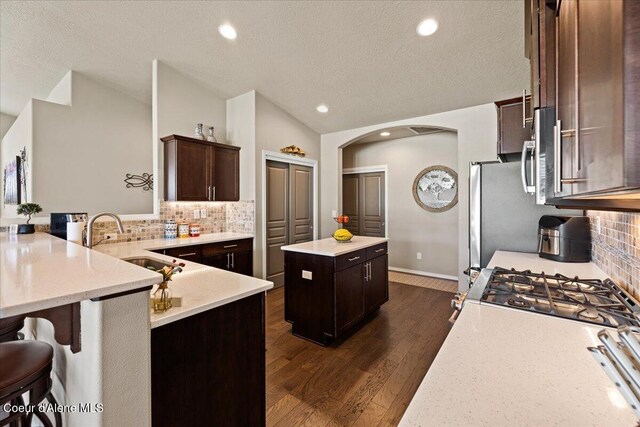3265 E Galway Cir, Post Falls, ID 83854 - kitchen featuring a center island, arched walkways, a textured ceiling, backsplash, and dark wood-style floors