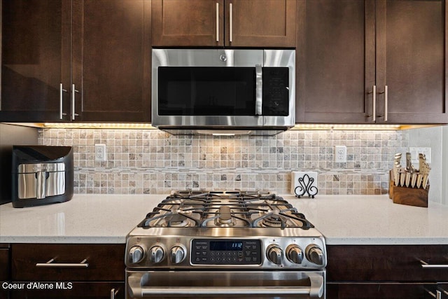 3265 E Galway Cir, Post Falls, ID 83854 - kitchen featuring stainless steel appliances, dark brown cabinetry, light stone counters, and decorative backsplash