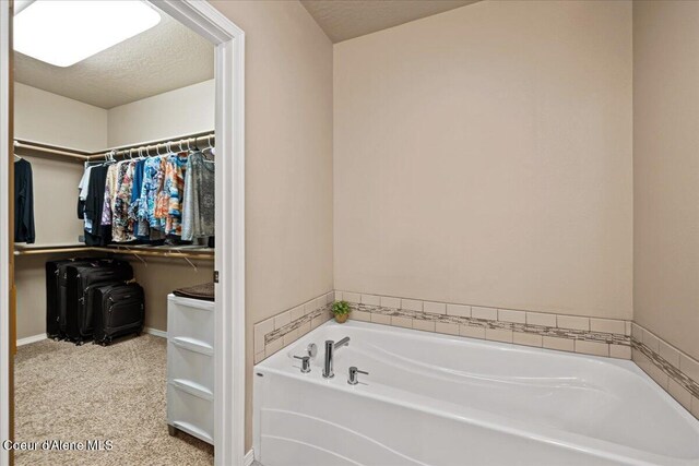 3265 E Galway Cir, Post Falls, ID 83854 - bathroom with a garden tub, a spacious closet, and a textured ceiling