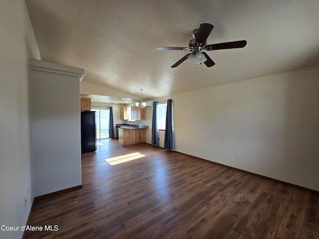 8706 W Sawtooth St, Rathdrum, ID 83858 - unfurnished living room with vaulted ceiling, dark wood finished floors, ceiling fan, a textured ceiling, and a chandelier