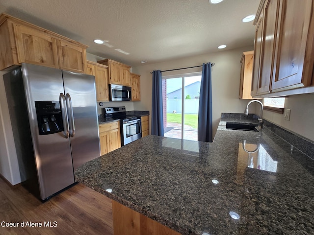 8706 W Sawtooth St, Rathdrum, ID 83858 - kitchen featuring stainless steel appliances, a peninsula, dark stone countertops, dark wood-style floors, and recessed lighting