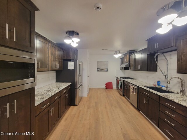 8706 W Sawtooth St, Rathdrum, ID 83858 - kitchen with appliances with stainless steel finishes, tasteful backsplash, light wood-style flooring, and dark brown cabinets