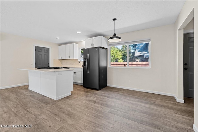 1038 N 15th St, Coeur Dalene, ID 83814 - kitchen featuring black fridge, light wood finished floors, white cabinetry, a kitchen island, and light countertops