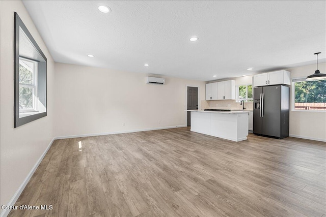 1038 N 15th St, Coeur Dalene, ID 83814 - unfurnished living room featuring light wood-style floors, a wall unit AC, recessed lighting, plenty of natural light, and a textured ceiling