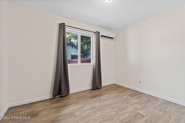 1038 N 15th St, Coeur Dalene, ID 83814 - spare room with wood finished floors, a wall mounted AC, and a textured ceiling