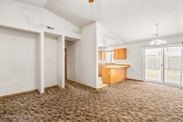 2533 W Grenoble Ln, Coeur Dalene, ID 83815 - kitchen featuring vaulted ceiling, light colored carpet, a peninsula, a chandelier, and hanging light fixtures