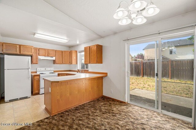 2533 W Grenoble Ln, Coeur Dalene, ID 83815 - kitchen with white appliances, vaulted ceiling, under cabinet range hood, healthy amount of natural light, and a peninsula