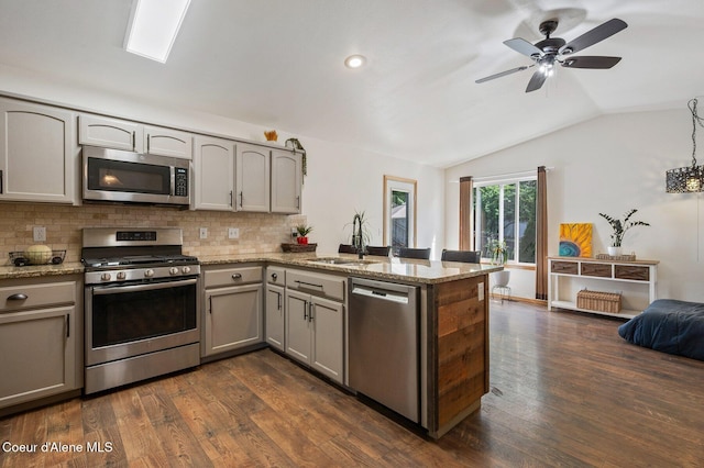 8562 N Audubon Dr, Hayden, ID 83835 - kitchen with appliances with stainless steel finishes, a peninsula, gray cabinets, lofted ceiling, and decorative backsplash