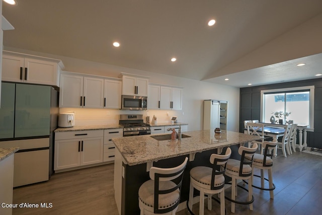 5987 W Quinn Way, Rathdrum, ID 83858 - kitchen featuring appliances with stainless steel finishes, lofted ceiling, white cabinetry, dark wood-style flooring, and a kitchen island with sink