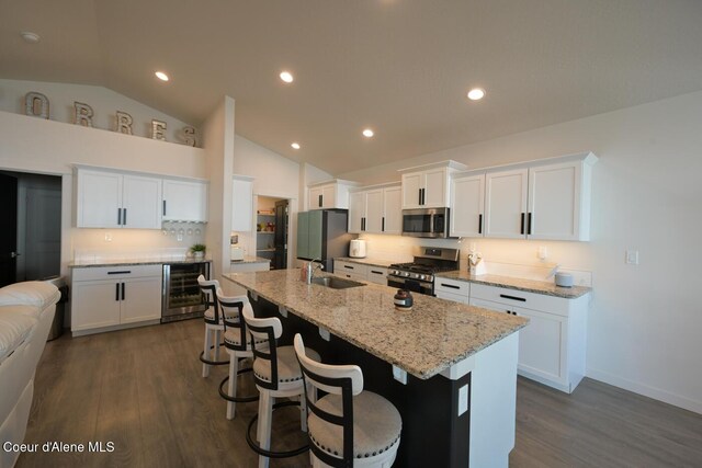 5987 W Quinn Way, Rathdrum, ID 83858 - kitchen featuring beverage cooler, stainless steel appliances, a kitchen island with sink, dark wood finished floors, and a breakfast bar