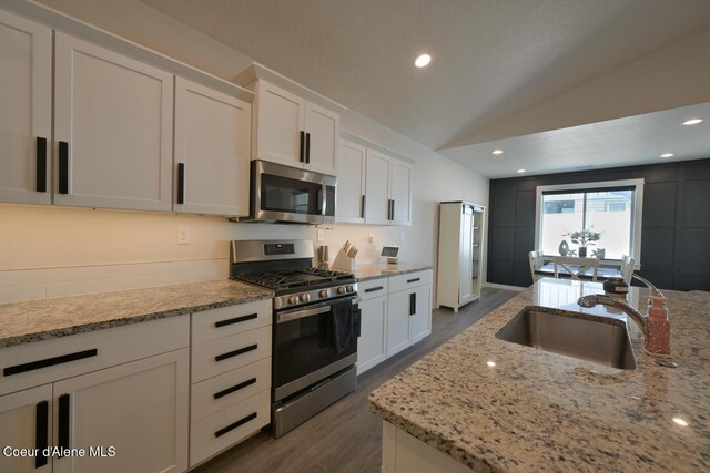 5987 W Quinn Way, Rathdrum, ID 83858 - kitchen with stainless steel appliances, dark wood finished floors, white cabinets, vaulted ceiling, and light stone counters